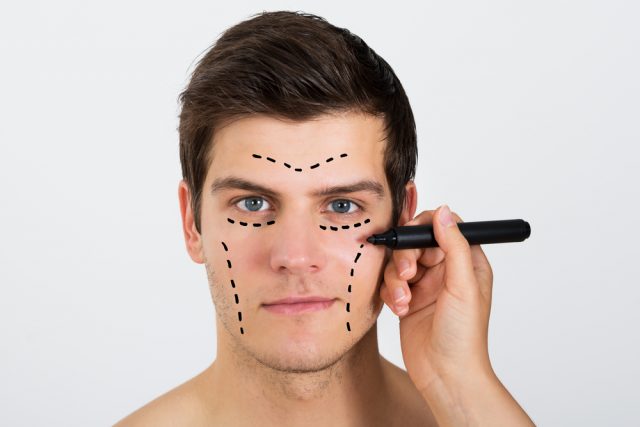 Woman Drawing dots on Young Man's Face