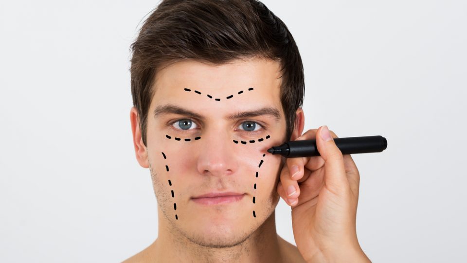 Woman Drawing dots on Young Man's Face